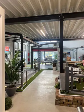 Moderne Ausstellungshalle mit Terrassenüberdachungen, Pflanzen und Gartenmöbeln.