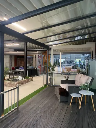 Moderne Terrassenüberdachung mit Glasdach, gemütlicher Sitzgruppe und Dekoration.