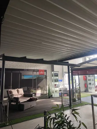 Überdachte Terrassen-Ausstellung mit modernen Markisen, Loungemöbeln und Pflanzen.