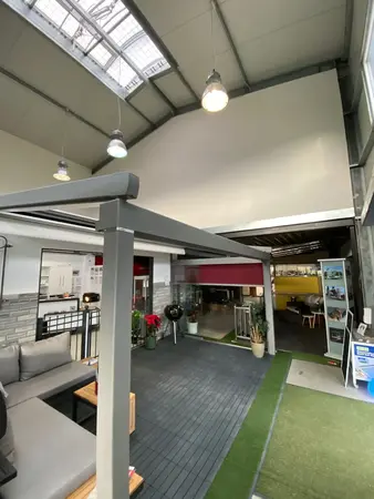 Moderner Ausstellungsraum für Terrassenüberdachungen mit Lounge-Möbeln und Grill.
