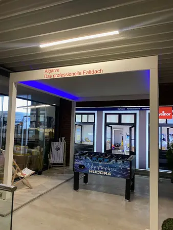 Modernes Faltdach Algarve mit LED-Beleuchtung, Kicker und Terrassenmöbeln in Ausstellung.