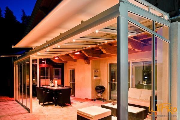 Moderne überdachte Terrasse mit Glasdach, stilvoller Beleuchtung und Gartenmöbeln.