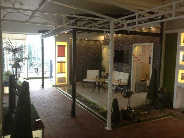 Überdachte Terrasse mit Sitzbank, Dekoration, Zierpflanzen und moderner Gartenanlage.