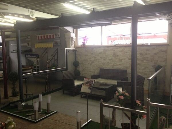 Moderne überdachte Terrasse mit Gartenmöbeln, Steindekorwand und Dekorationspflanzen.