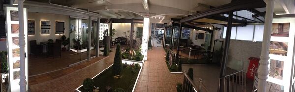 Innenansicht einer modernen Ausstellung mit Wintergärten, Terrassenüberdachungen und Gartenmöbeln.