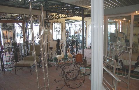 Ausstellung von schmiedeeisernen Gartendekorationen und Möbeln in einem Verkaufsraum.