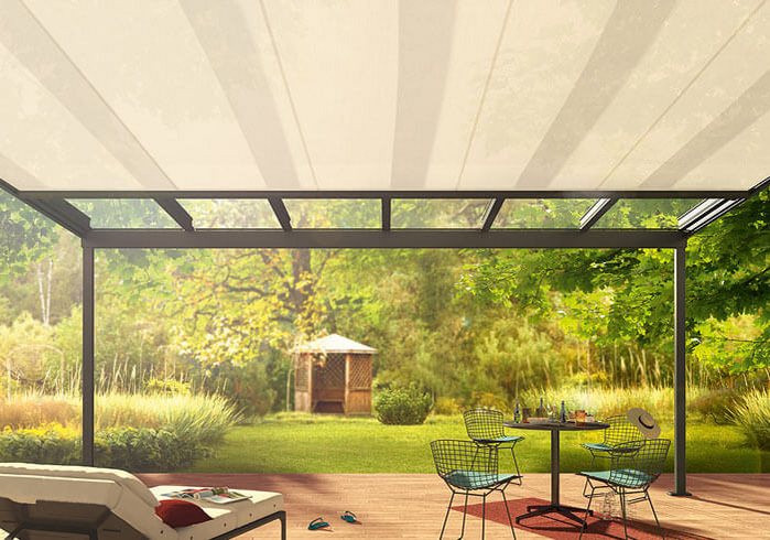 Moderne Terrassenüberdachung aus Glas im Garten mit Gartenmöbeln und Ausblick ins Grüne.